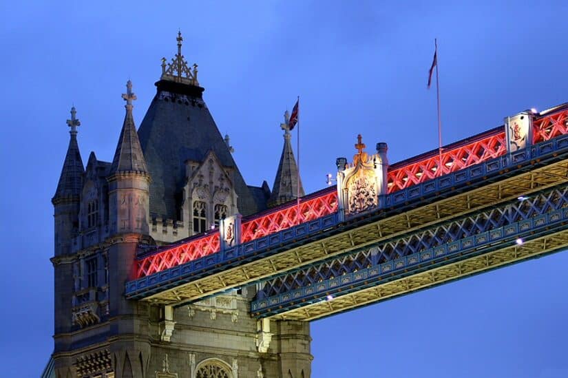 A Tower Bridge, uma das melhores atrações de Londres, brilha ao anoitecer com seus detalhes iluminados em vermelho e azul contrastando lindamente com o céu nublado.