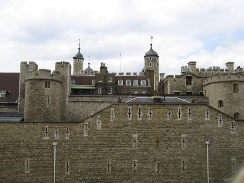 Uma fortaleza de pedra com torres e muros ameados ergue-se sob um céu nublado, lembrando as melhores atrações de Londres.
