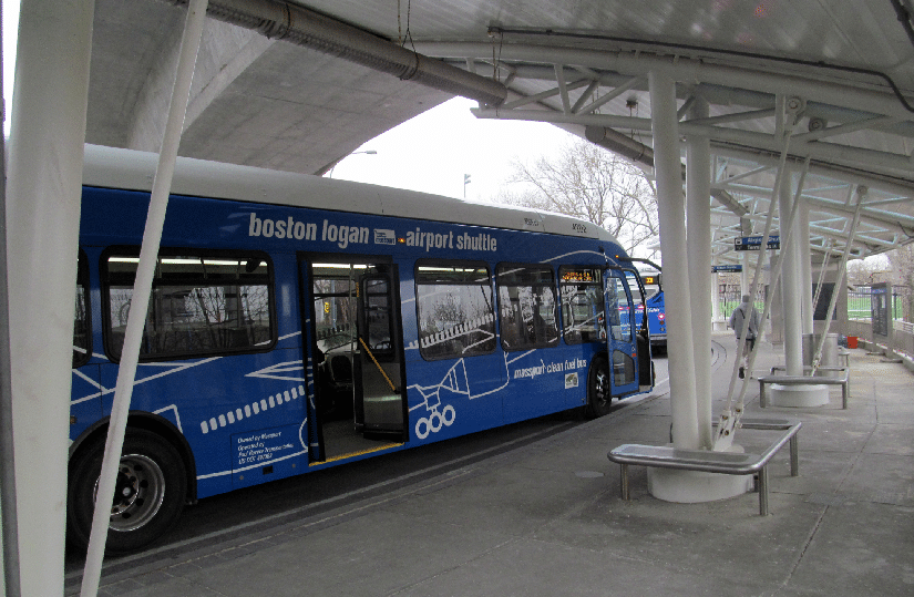 Um ônibus azul de transporte para o aeroporto estacionado em um ponto de ônibus sob uma cobertura perto do Aeroporto de Boston.