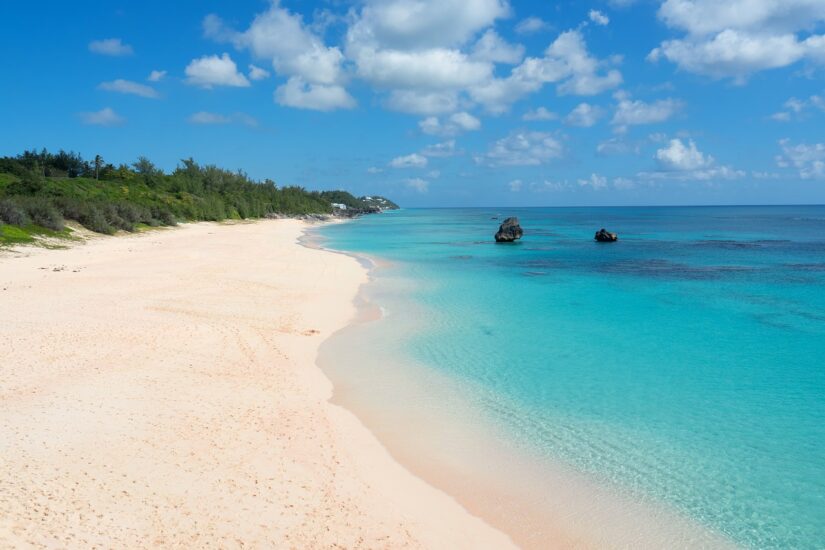 Uma praia tropical nas Bermudas com areia rosa, água azul turquesa e céu azul – ideal para uma viagem segura para Bermudas.