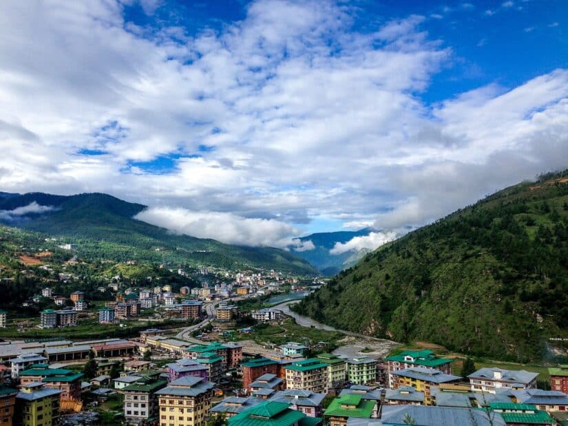 Uma cidade vibrante com edifícios coloridos, aninhada entre colinas verdes, perfeita para quem busca seguro viagem para Butão.