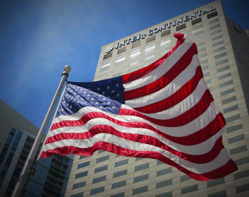 Bandeira dos EUA tremulando diante de um alto hotel InterContinental - ideal para quem busca viagem segura para a Flórida.