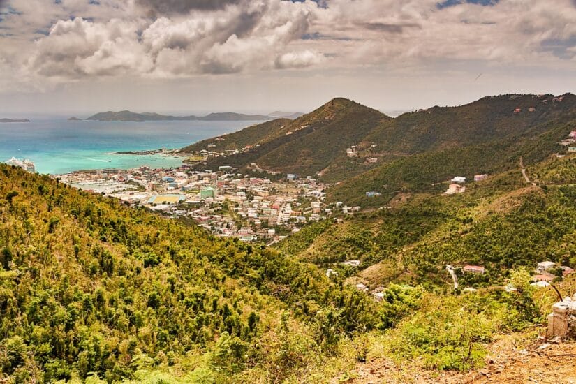 Paisagem montanhosa com uma cidade costeira à beira mar azul-turquesa – perfeita para quem busca viagem segura para Ilhas Virgens Britânicas.