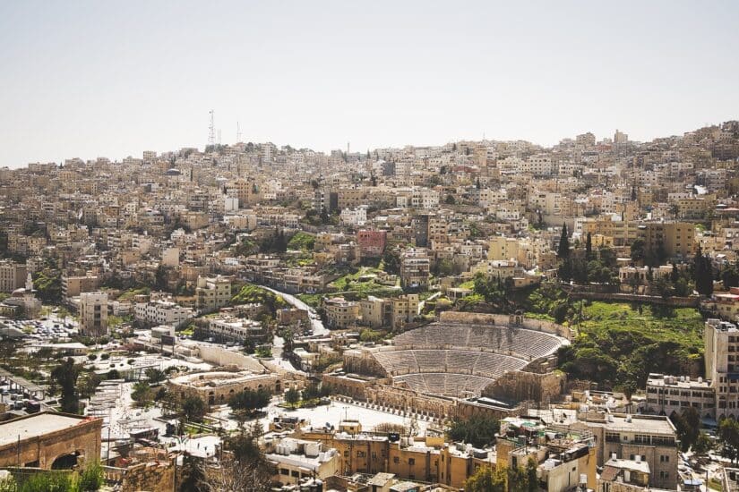 Vista de uma paisagem urbana com um grande anfiteatro romano antigo - ideal para quem busca viagem segura para Jordânia.