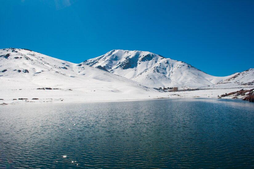 Montanhas cobertas de neve sob um céu azul claro, como uma cena antes da sua aventura de seguro viagem para Marrakesh.
