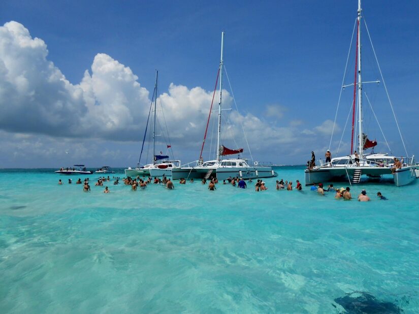 Catamarãs ancorados em águas azul-turquesa cristalinas enquanto grupos aproveitam o sol — explore com facilidade usando o eSIM Ilhas Cayman.