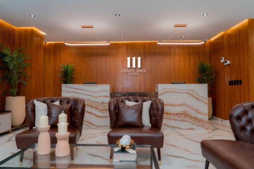 Saguão de hotel boutique em San Andrés: mesa de mármore, cadeiras de couro marrom, paredes de madeira e iluminação moderna.