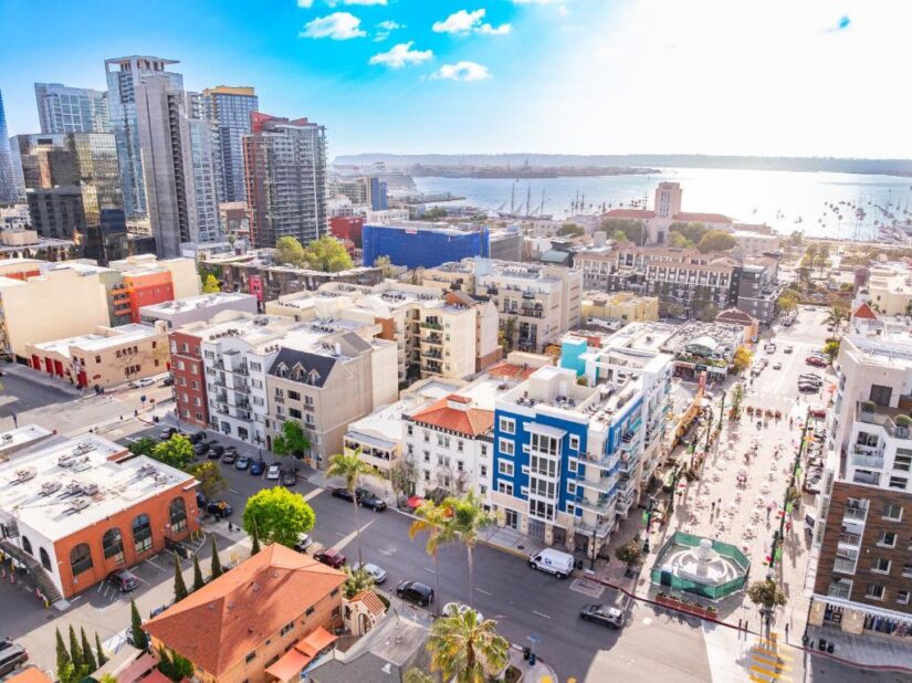 Vista aérea de onde ficar em San Diego, mostrando uma rua movimentada da cidade à beira-mar com prédios altos e barcos ao longe.