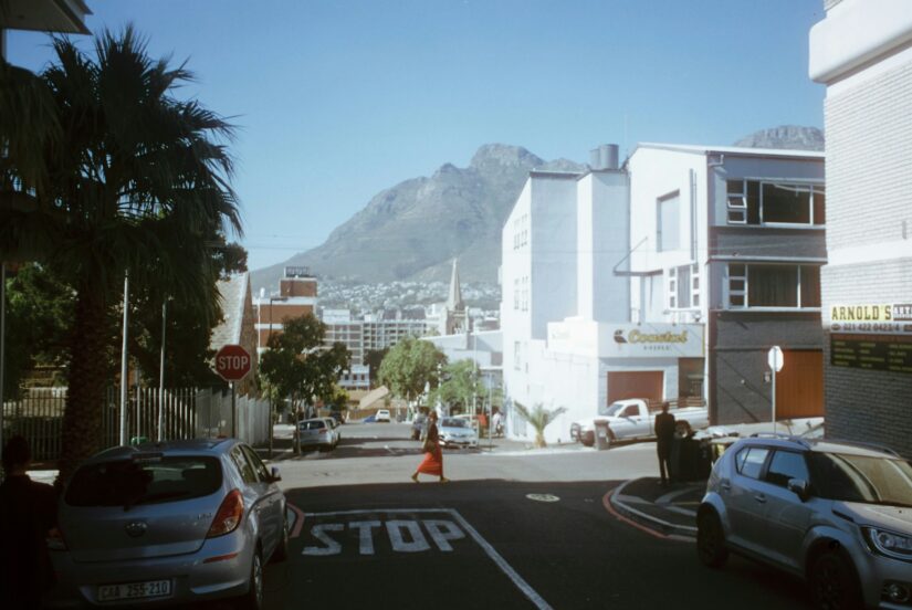 onde ficar em Cape Town no bairro De Waterkant na África do Sul Uma rua da cidade na Cidade do Cabo com carros, palmeiras e montanhas - perfeita para explorar a África do Sul.