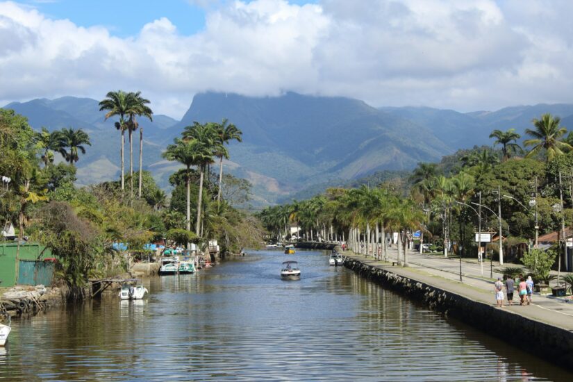 onde ficar em Paraty no bairro caborê Canal ladeado por palmeiras e barcos, montanhas ao fundo - uma vista clássica para quem procura hotéis no Caborê no RJ.