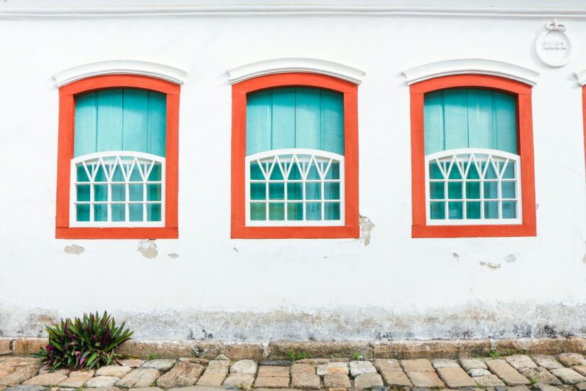 onde ficar em Paraty no centro urbano Três janelas turquesa com acabamento vermelho em Parati, acima de um caminho de pedra .