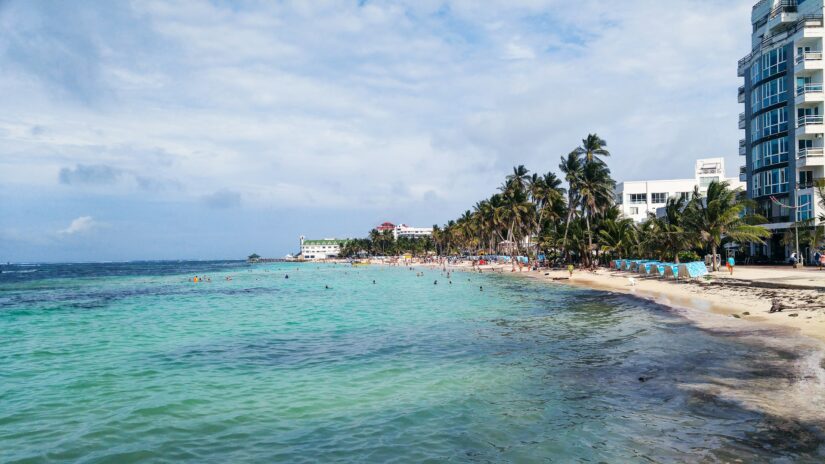 hotéis em north end na colômbia Praia tropical com água azul-turquesa, palmeiras, pessoas nadando e onde ficar em San Andrés ao longo da costa.