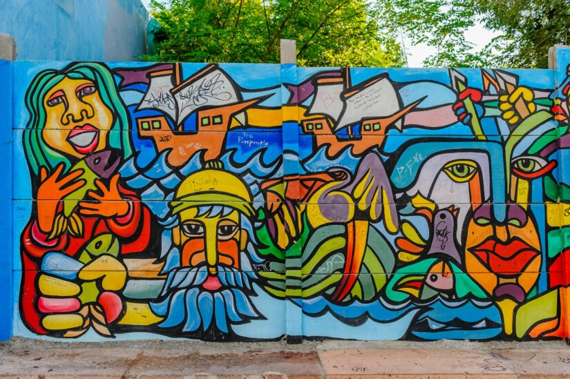 onde ficar em Santiago no Barrio Brasil Chile Mural colorido com rostos abstratos, mãos, peixes, casas, ondas e linhas vibrantes na capital do Chile..