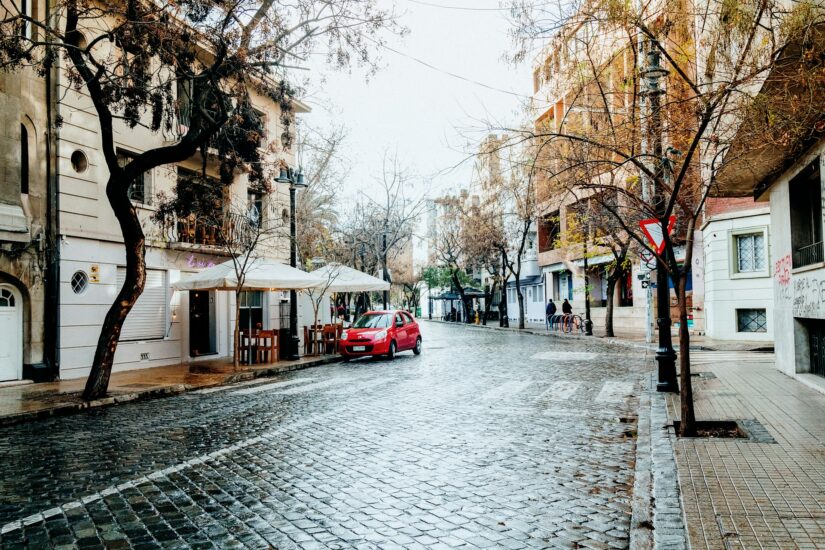 onde ficar em Santiago no bairro Bellas Artes ou Lastarria Um carro vermelho estacionado em uma rua tranquila de paralelepípedos, como os lugares que você encontrará ao pesquisar hotéis no Chile