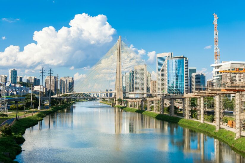 Bairros seguros em SP Itaim Bibi Moderna Ponte Estaiada sobre o Rio Pinheiros com edifícios da cidade - onde ficar em São Paulo - com o céu azul ao fundo.