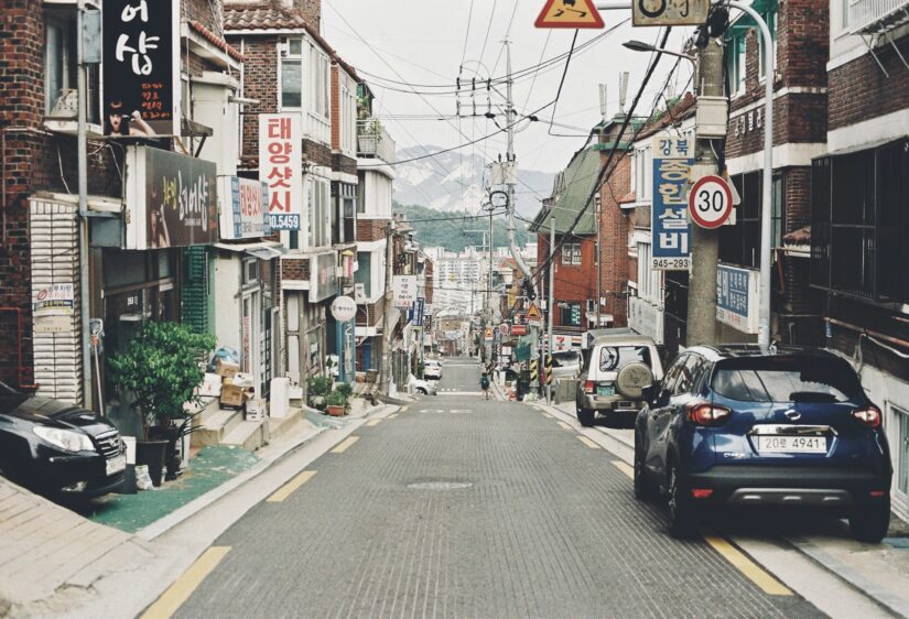 onde ficar em Seul em Seongsu-dong na Coreia do Sul Uma rua inclinada em um bairro coreano sugere , com carros estacionados e placas Hangul em prédios de tijolos.