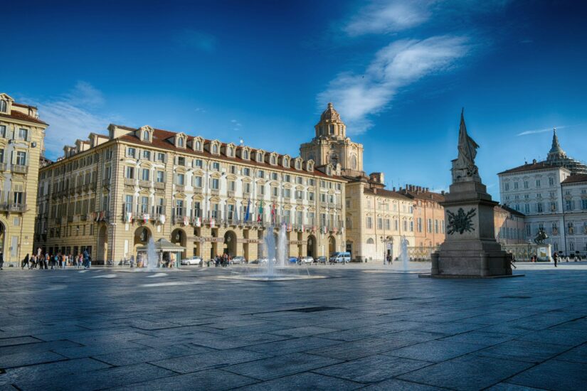 melhores hotéis no centro histórico de torino na itália Praça ensolarada da cidade com edifícios históricos - perfeita para explorar enquanto você decide o onde ficar em Turim sob um céu azul brilhante.