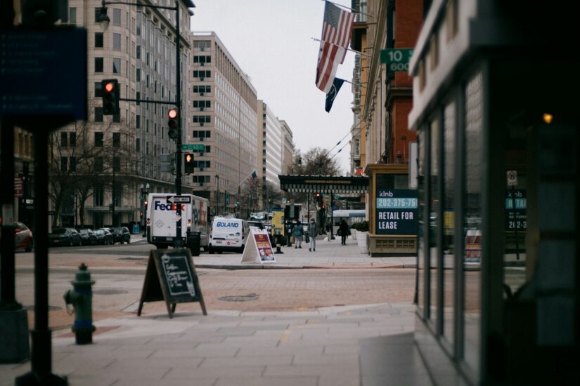 Um cruzamento de rua da cidade com prédios, placas, um caminhão da FedEx e dicas de onde ficar em Washington em um dia nublado.