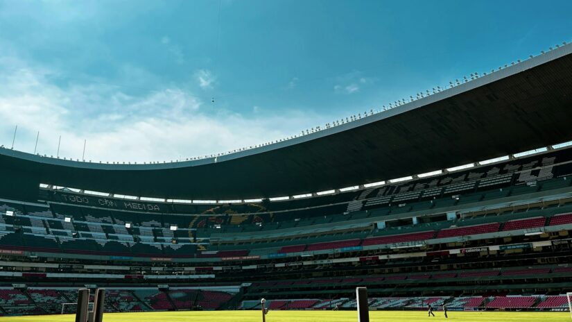 hotéis perto do Estádio Azteca Uma visão ampla do estádio azteca vazio com assentos vermelhos e brancos sob um céu azul, perfeito para onde ficar na Cidade do México.