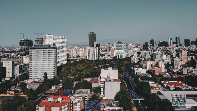 onde ficar na Cidade do México em Polanco Vista aérea do México com prédios altos, ruas arborizadas e montanhas distantes sob um céu claro.