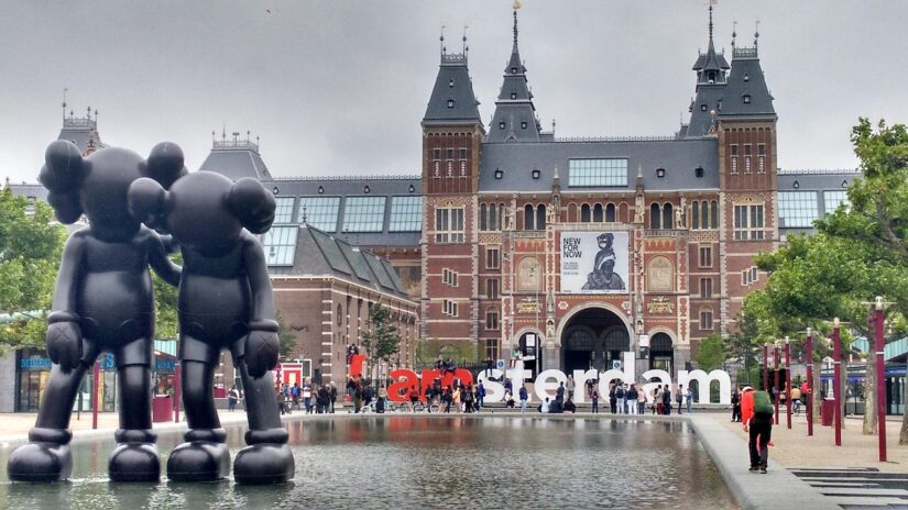 Duas grandes estátuas negras ao lado de um espelho d'água perto da placa I amsterdam - perfeito para fotos de onde ficar em Amsterdã.