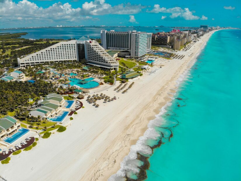 melhores hotéis e resorts na Zona Hoteleira Leste no México Vista aérea de onde ficar em Cancún na Zona Hoteleira Leste, com resorts à beira-mar e águas azul-turquesa ao longo de uma costa arenosa.