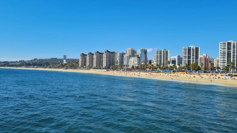 onde ficar em Valparaíso e em Viña del Mar Prédios altos ao longo de uma praia de areia na cidade de Viña del Mar no Chile ao lado do oceano azul calmo e do céu claro e brilhante.
