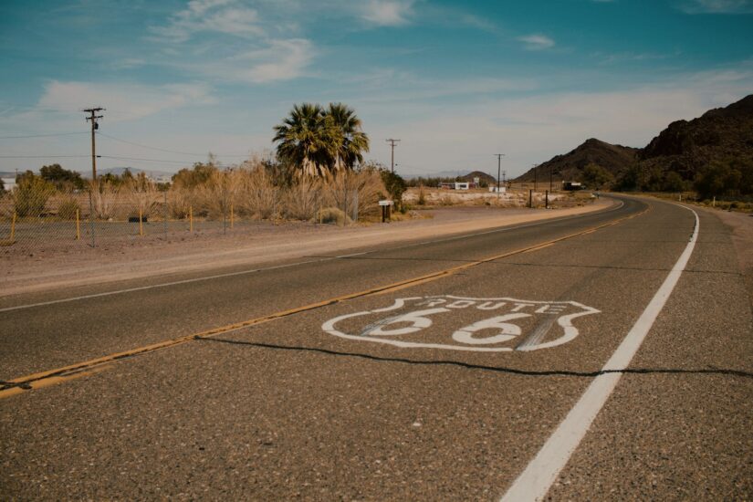 onde ficar no Grand Canyon em Valle. Uma rodovia ensolarada no deserto com a Route 66, curvando-se entre as palmeiras - perfeita para quem procura hotéis no Valle.