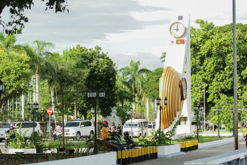 onde ficar em Díli no Bairro Central perto do Palácio do Governo Um grande monumento no Palácio do Governo do Timor-Leste, cercado por árvores e carros.