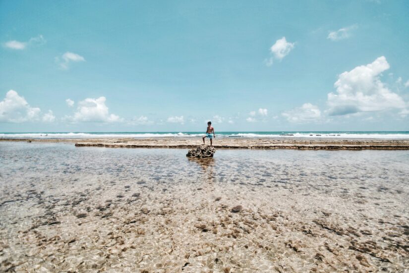 onde ficar em Porto de Galinhas na Praia de Maracaípe Pessoa em pé sobre rochas em águas rasas e claras do oceano na Praia de Maracaípe em Ipojuca.