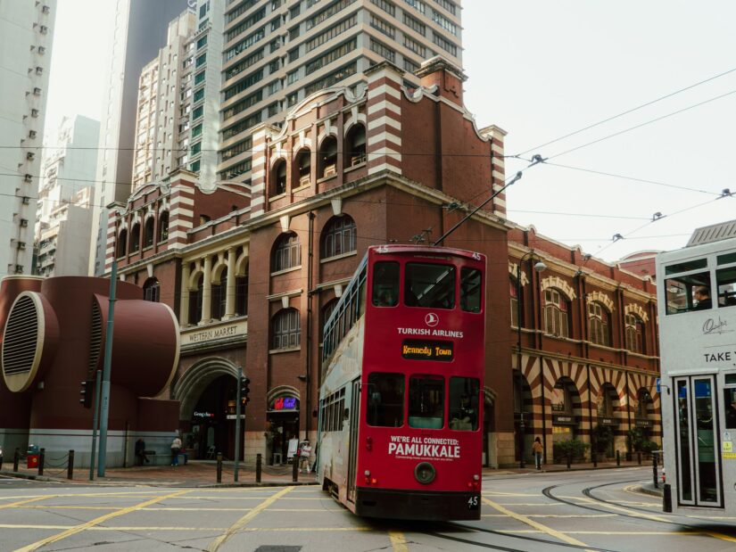 melhores hotéis em Sheung Wan Um bonde vermelho de dois andares passa por um prédio histórico em Sheung Wan - vistas clássicas ao explorar onde ficar em Hong Kong.