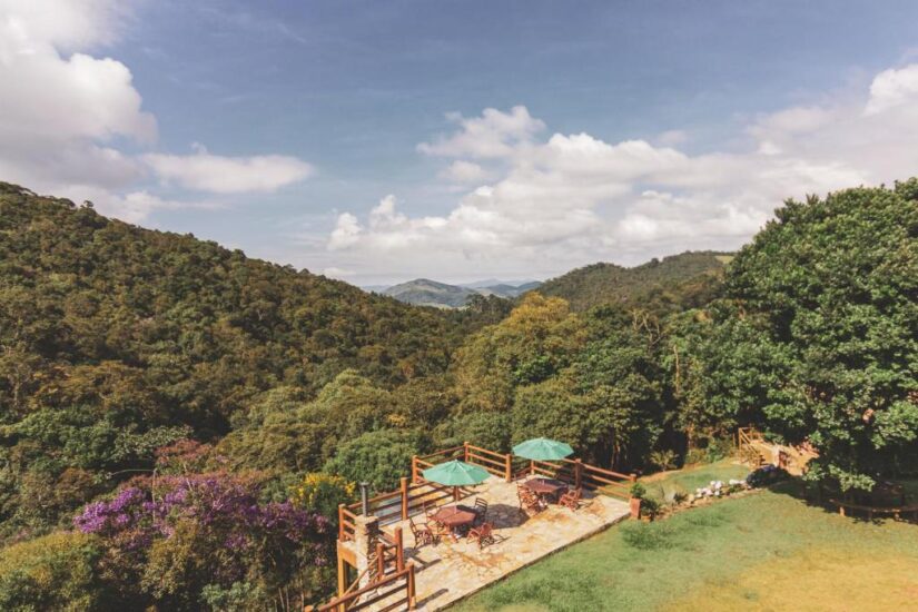 onde ficar em Ibitipoca na Estrada Parque do Ibitipoca em Minas Gerais Um terraço com mesas e guarda-sóis verdes, perfeito para relaxar no interior de Minas Gerais perto do Parque de Ibitipoca.
