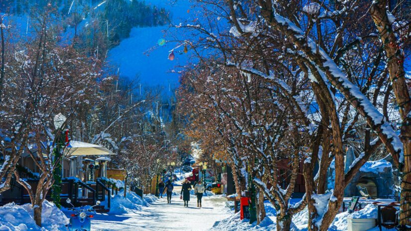 melhores hotéis na neve no Colorado nos EUA Ruas cobertas de neve repletas de árvores e pessoas caminhando, montanhas além - perfeito para quem procura onde ficar em Aspen Downtown.