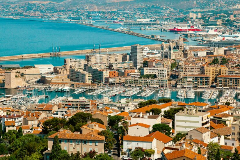 onde ficar em Marselha em La Joliette na França Vista aérea do Porto Velho de Marsielle com o bairro La Joliette ao fundo, com barcos, edifícios históricos e o mar ao fundo.