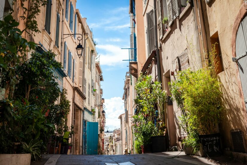 onde ficar em Marselha em Le Panier Rua estreita e iluminada pelo sol, repleta de plantas e prédios em tons pastéis - perfeita para encontrar hotéis em Le Panier em Marseille