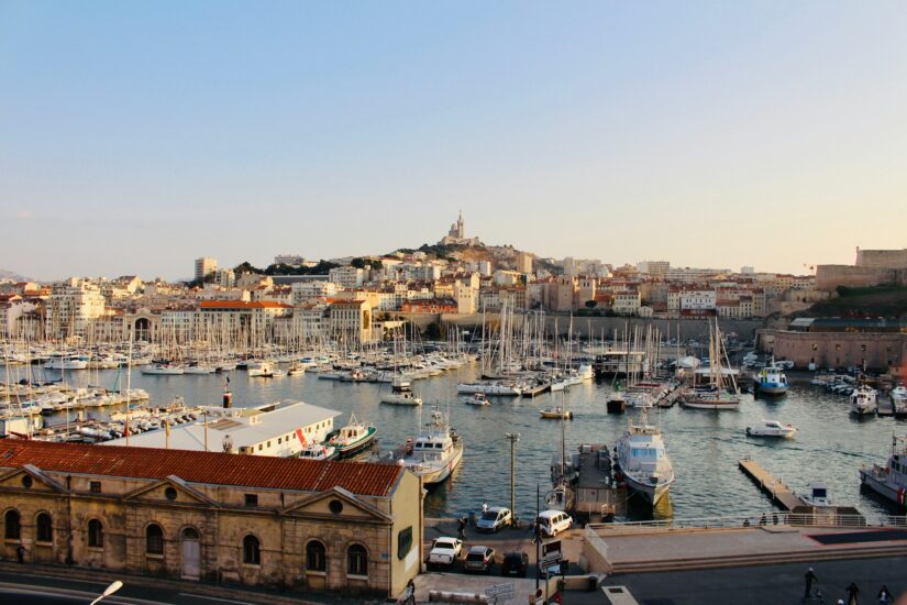 hotéis perto do Vieux-Port na França Porto repleto de barcos e iates, prédios da cidade atrás, igreja na encosta - ideal para decidir onde ficar em Marselha no Porto Antigo Vieux-Port