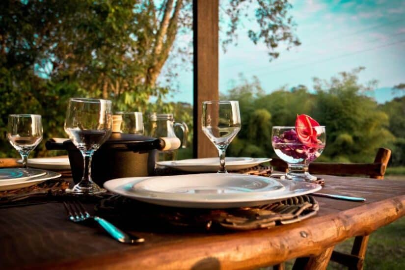 Mesa de jantar ao ar livre com pratos, copos e uma sobremesa, cercada por natureza e vegetação demonstrando onde ficar em Morretes