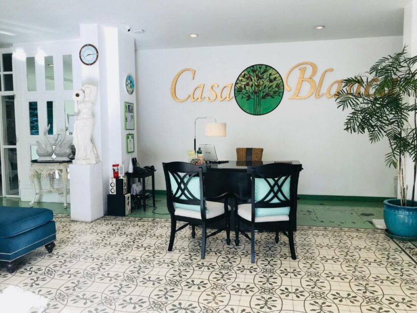 Balcão de recepção com duas cadeiras, azulejos decorativos e placa da Casa Blanca em um saguão brilhante e elegante Onde ficar em Phuket.