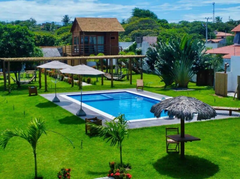 Uma piscina retangular com guarda-sóis e espreguiçadeiras, perfeita para quem procura onde ficar em Canoa Quebrada.
