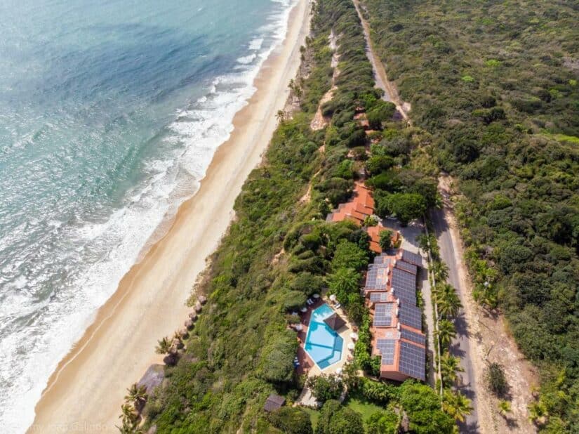 Vista aérea de um resort onde ficar em Pipa à beira-mar com piscina, cercado por vegetação e uma costa de areia.