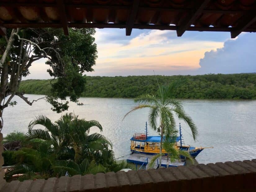 Um barco colorido em um rio, cercado por árvores exuberantes, visto de um pátio sombreado ao pôr do sol onde ficar em Prado