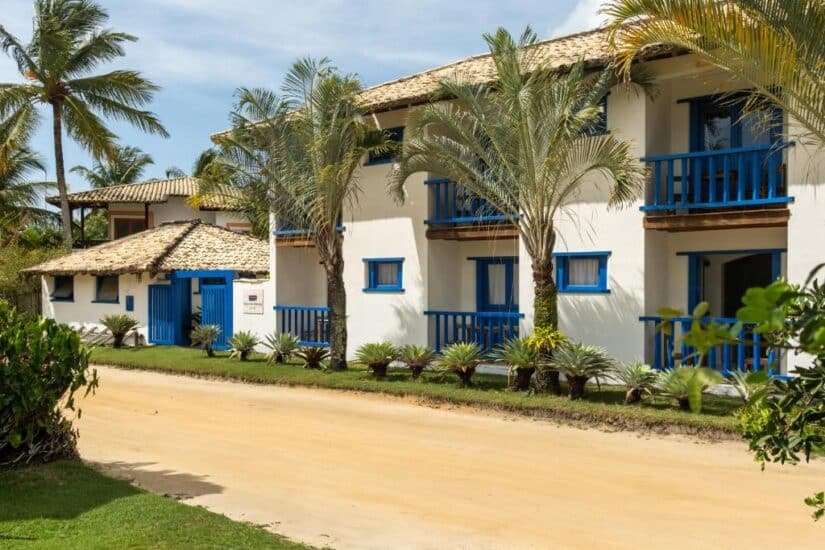pousadas no sul da Bahia Edifício branco com acabamento azul, varandas e palmeiras - um local ideal onde ficar na Praia do Espelho no interior da vila