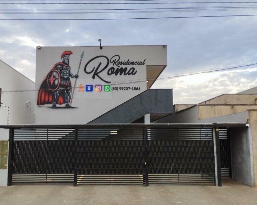 Entrada do Residencial Roma com um mural de um soldado romano e detalhes de contato na fachada do edifício.