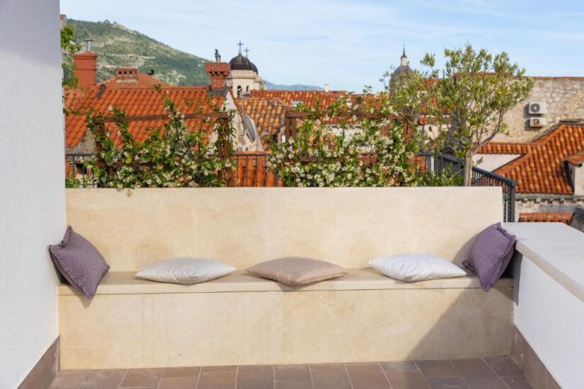 hotéis na Cidade Antiga na Croácia Banco de pedra com quatro almofadas em um terraço, perfeito para relaxar enquanto explora onde ficar em Dubrovnik na Cidade Antiga.