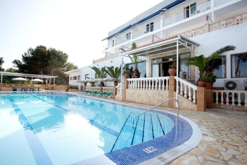 Piscina ensolarada de hotel com águas cristalinas, espreguiçadeiras e palmeiras — ideal se você estiver procurando onde se hospedar em Formentera.