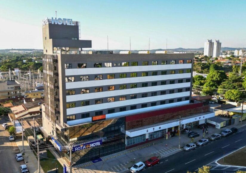 Um hotel alto com uma placa que diz “HOTEL” — perfeito para quem procura onde se hospedar em Goiânia — com carros e prédios da cidade ao redor.