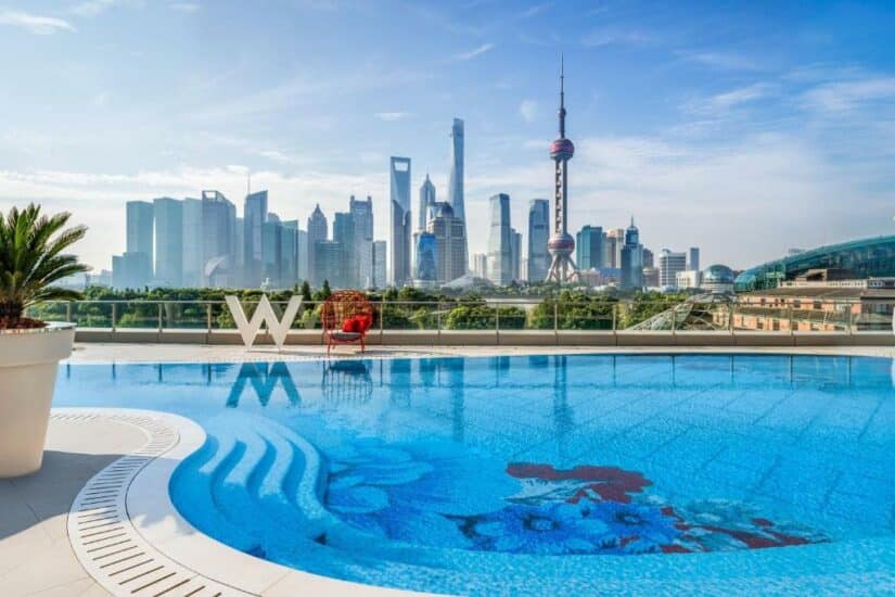 Piscina na cobertura com vista para o horizonte da cidade e arranha-céus modernos ao fundo em um dia claro.