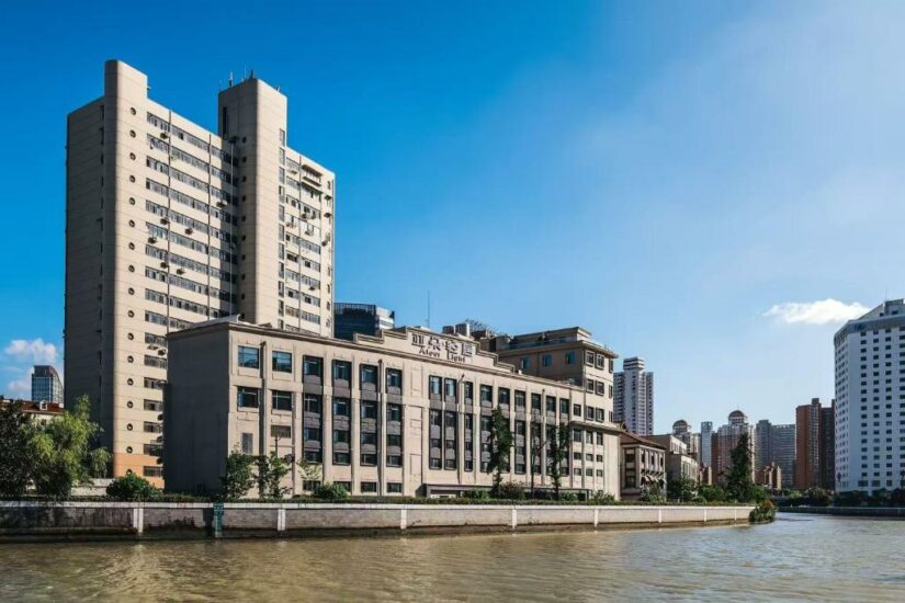Uma vista ribeirinha de edifícios altos e modernos sob um céu azul claro em uma área urbana.