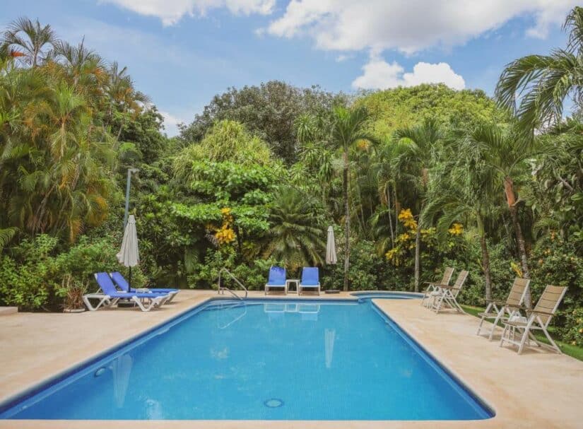 Piscina externa retangular cercada por palmeiras, espreguiçadeiras e guarda-sóis em um dia ensolarado onde ficar na Costa Rica.