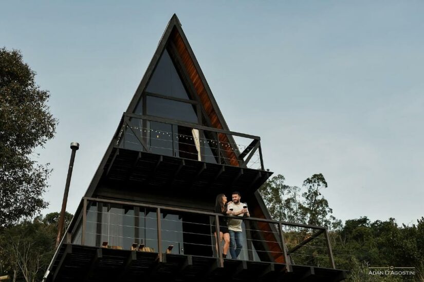 onde ficar em Ametista do Sul no Rio Grande do Sul Cabine de estrutura de madeira com varanda; um casal está do lado de fora, cercado por árvores sob um céu claro.